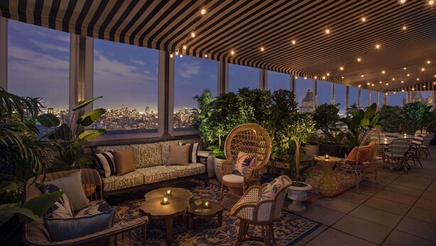 A rooftop lounge with a striped ceiling, large windows, and a city view. - Park Lane New York (New York)