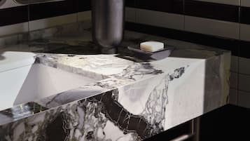A bathroom with a marble sink, a vase of flowers, and a mirror.