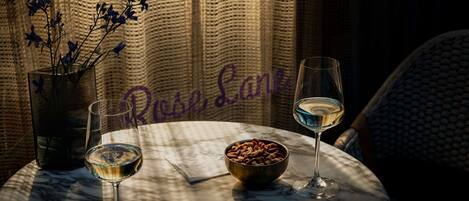 A table with two wine glasses, a bowl of nuts, and a vase of flowers.