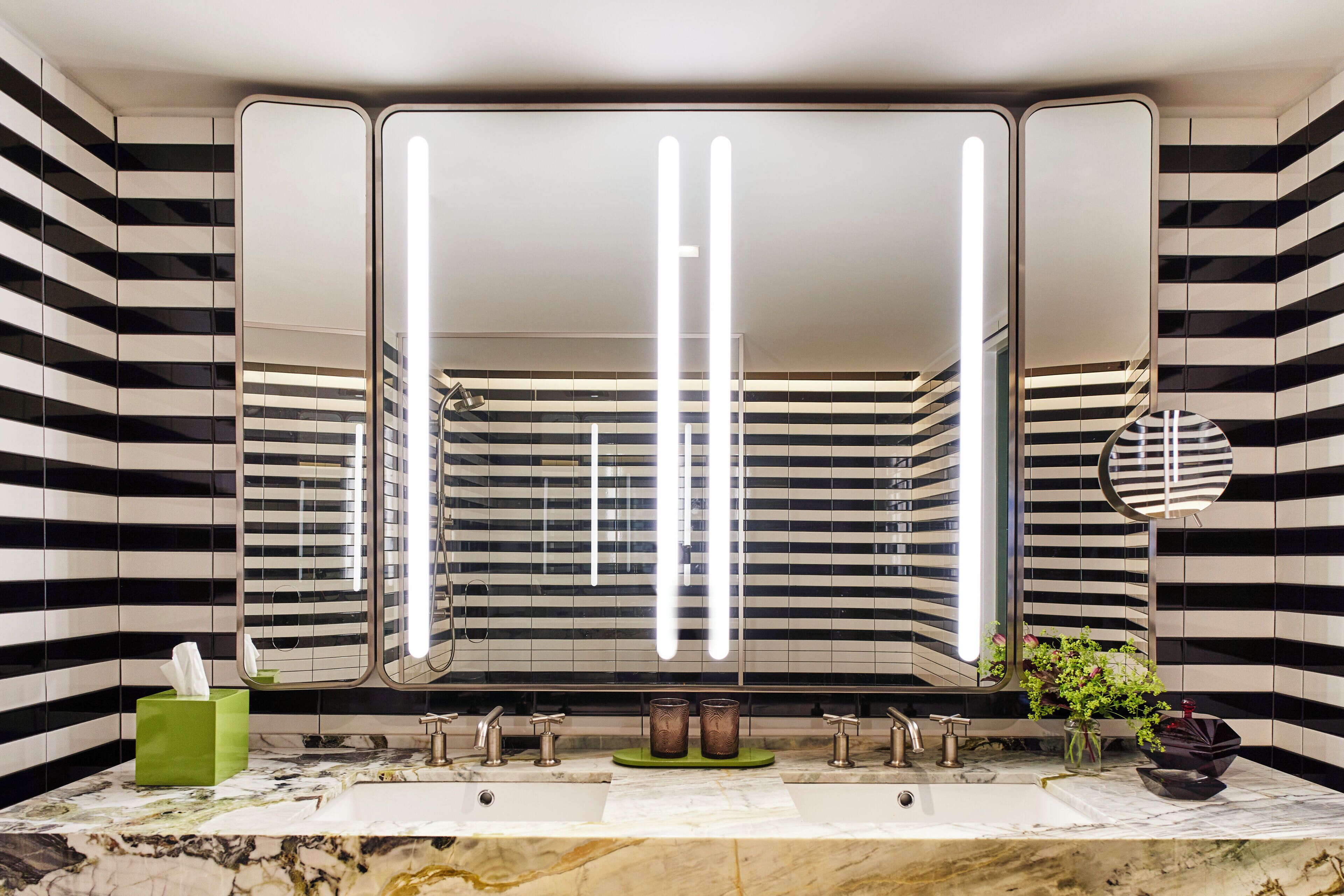 A bathroom with a large mirror, two sinks, and a green tissue box.