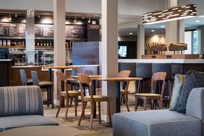 Um saguão de hotel moderno com áreas de estar, um bar e um quadro de cardápio.