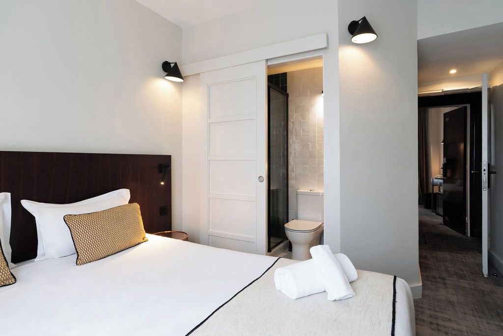 Una habitación de hotel con cama, baño y pasillo.
