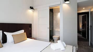 Una habitación de hotel con cama, baño y pasillo.