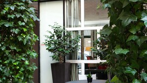 An outdoor patio area with a round table and two chairs, surrounded by potted plants. - Hotel Eiffel Seine (Paris)