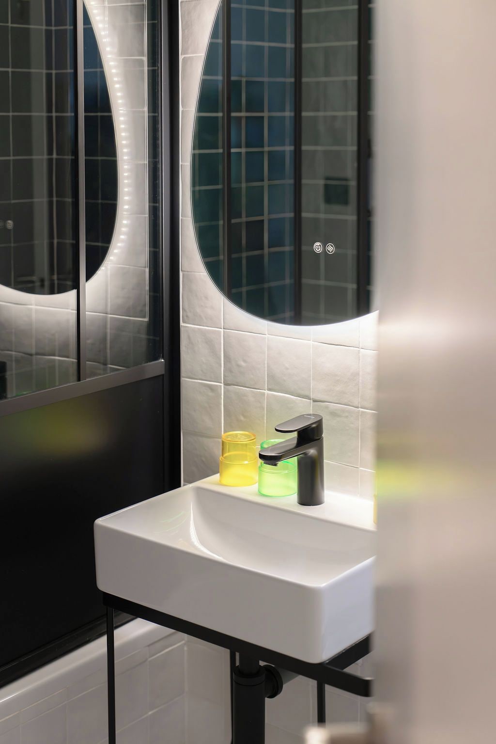 Une salle de bain moderne avec un lavabo blanc, un robinet noir et deux distributeurs de savon.