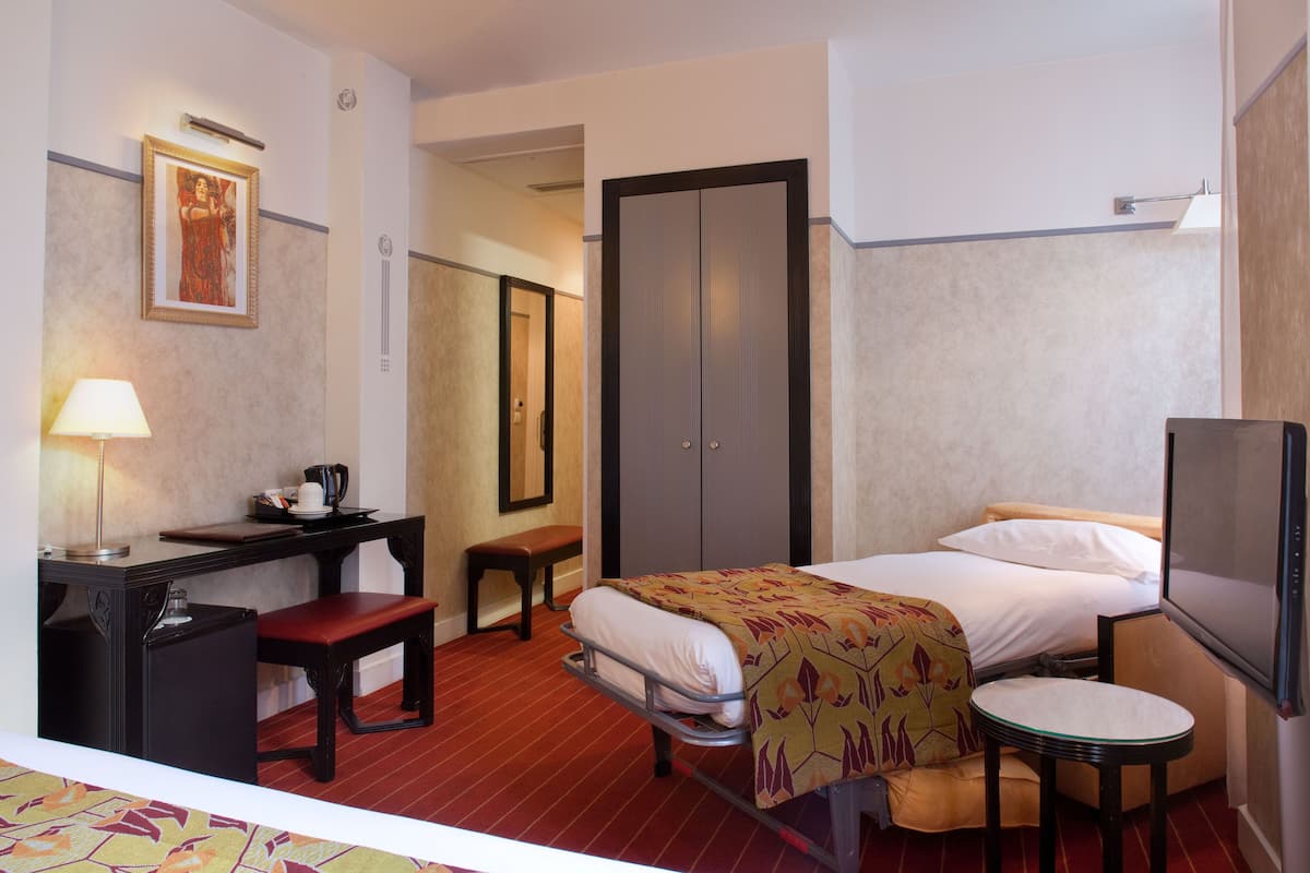 Ein Hotelzimmer mit Bett, Nachttisch, Stuhl, Schreibtisch, Lampe und Fernseher.