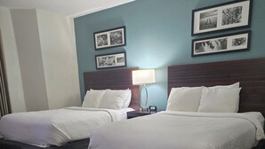 A hotel room with two beds, a nightstand with a lamp, and framed pictures on the wall. - Sleep Inn Chattanooga Hamilton Place (Chattanooga)