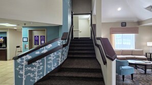 A staircase leading to a second floor with a blue railing, a reception desk, and a seating area with a sofa and coffee table. - Sleep Inn Chattanooga Hamilton Place (Chattanooga)