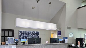 A hotel reception desk with a digital check-in station, a large framed artwork, and a black doormat. - Sleep Inn Chattanooga Hamilton Place (Chattanooga)