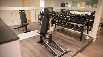 Een sportschool met gewichthefriepentuien en een rek met dumbbells.