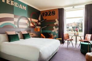 Relax in this stylish room with a large bed, round table, and city view.