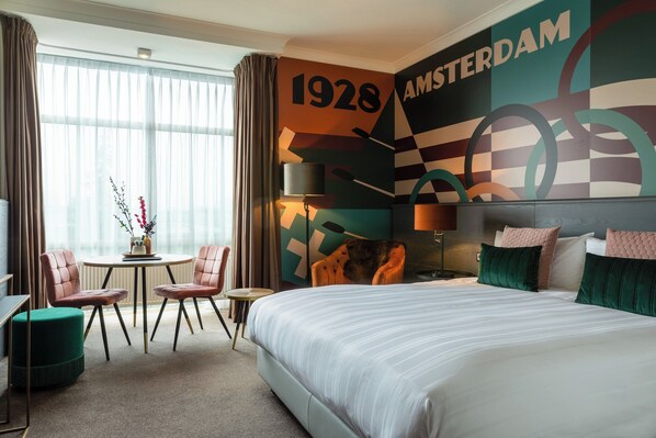 Relax in a stylish room with a large bed, round table, and vibrant mural.