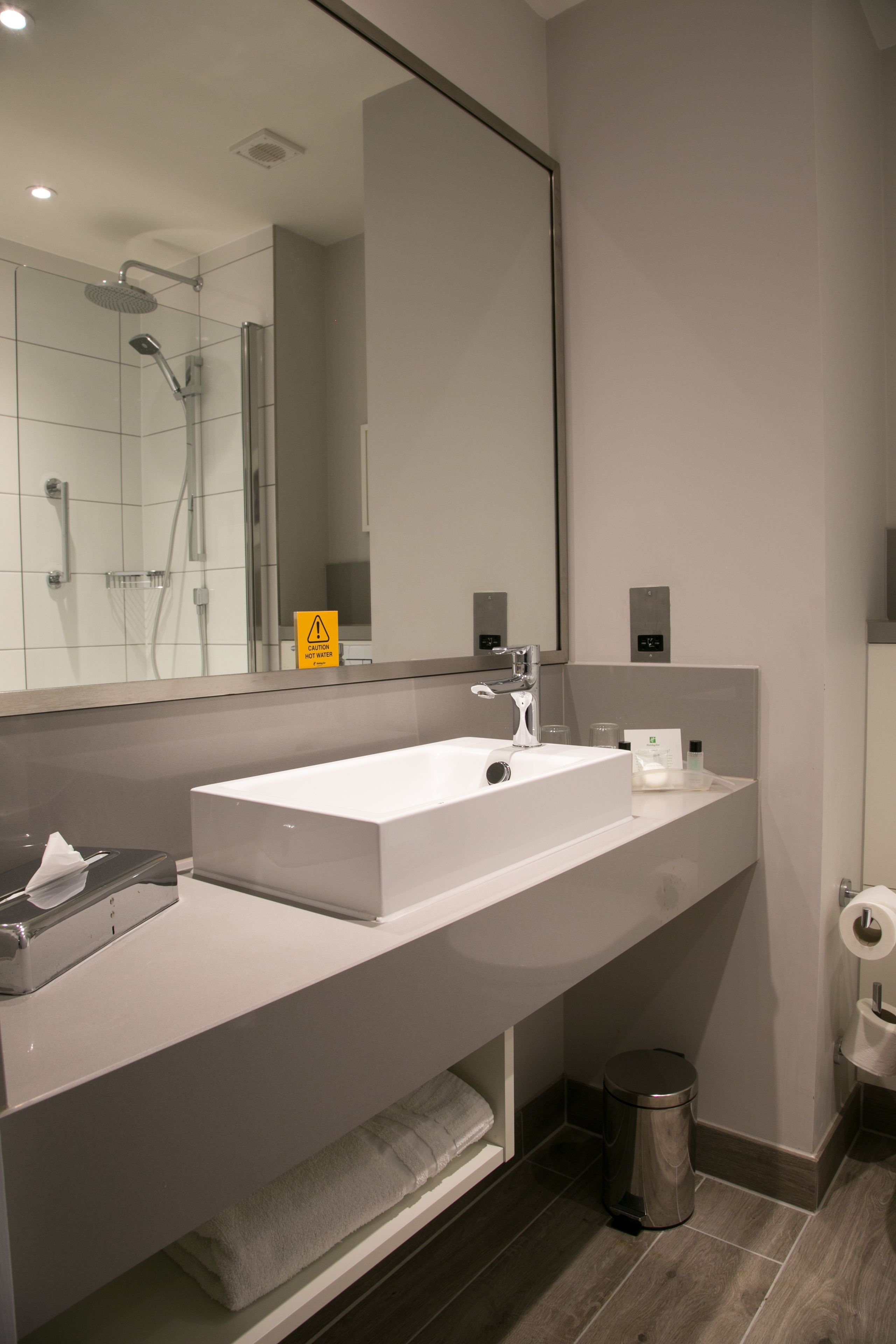 Un baño moderno con un espejo grande, un lavabo blanco y una zona de ducha.