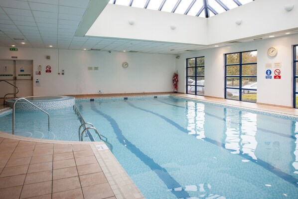 Swimmers can enjoy the pool surrounded by safety signs and exit doors.