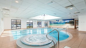 An indoor swimming pool with a hot tub, large windows, and a beach mural on the wall. - Holiday Inn London - Shepperton by IHG (Shepperton)