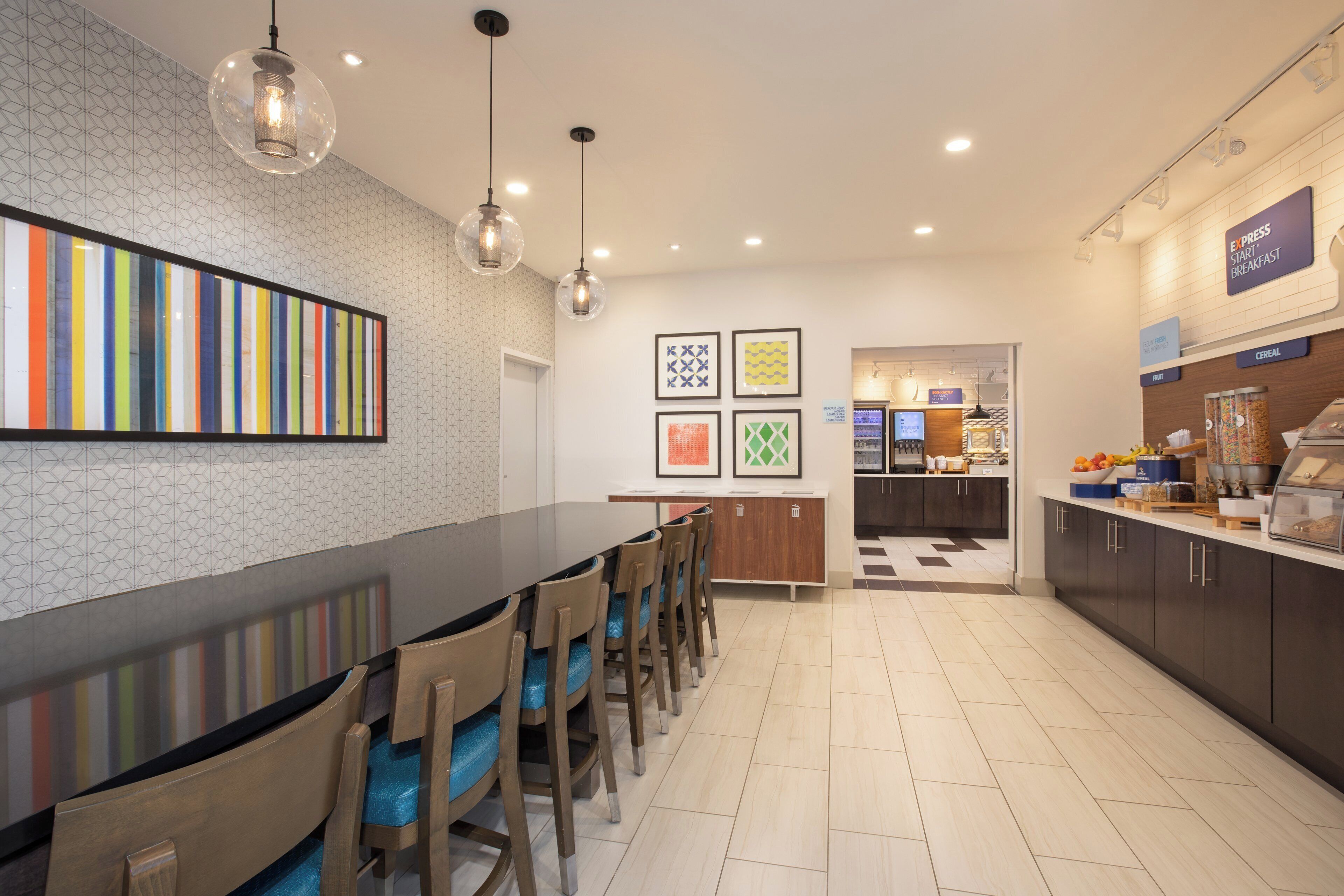 A modern kitchen with a long counter, multiple chairs, and overhead lighting.