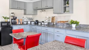 Una cocina moderna con gabinetes grises, sillas rojas y encimeras de granito.