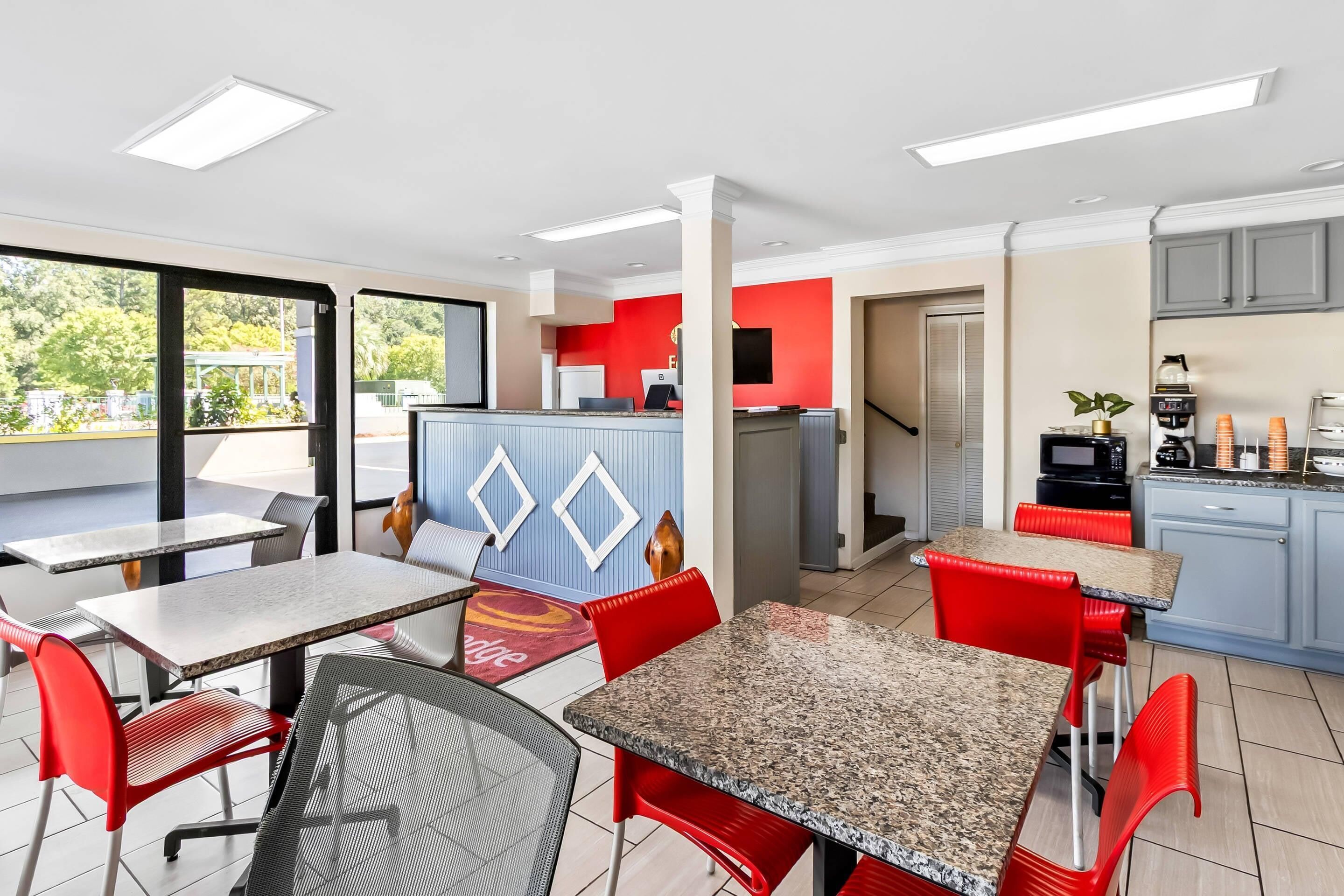 Habitación de hotel moderna con zona de comedor, cocina y ventanas amplias que ofrecen vistas al exterior.