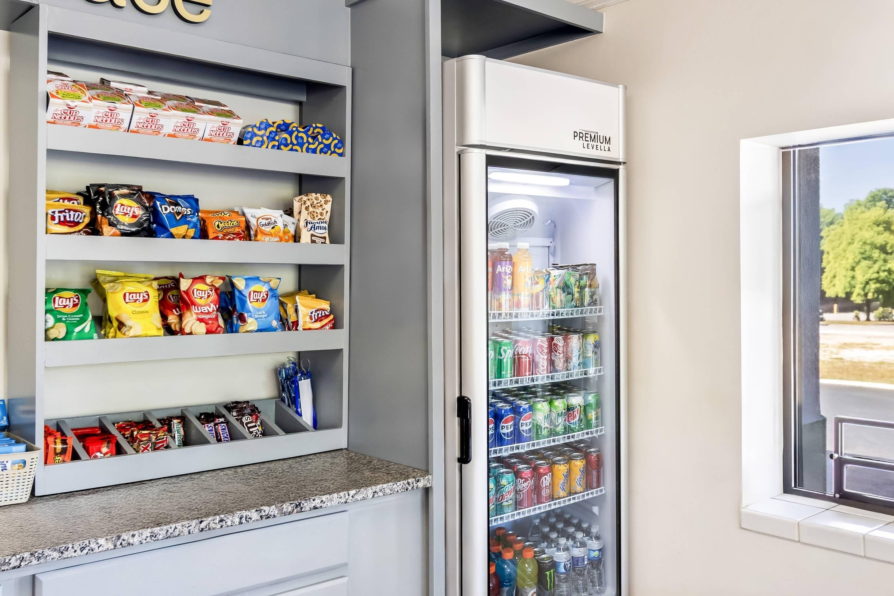 A snack and beverage refrigerator stocked with various brands and types of snacks and drinks.