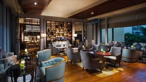 A modern lounge with a bar area, comfortable seating, and a view of the cityscape. - Artyzen Grand Lapa Macau (Macau)