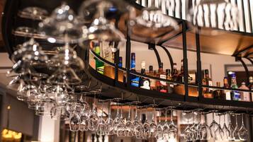 A bar area with multiple wine glasses hanging from a rack and a variety of liquor bottles on shelves.