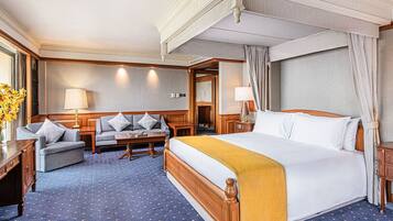 A hotel room with a large bed, a sofa, a small table, and a desk.