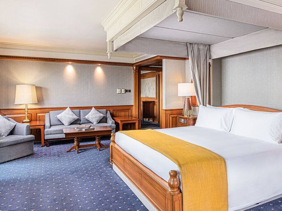 A hotel room with a large bed, a sofa, a small table, and a desk.