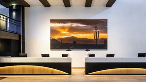 A reception area with a large desert sunset painting, two reception desks, and a wooden floor.