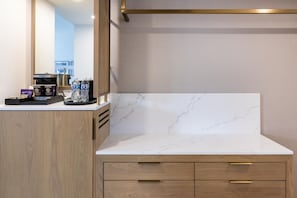 A modern bathroom with a marble countertop, wooden cabinetry, and a mirror.