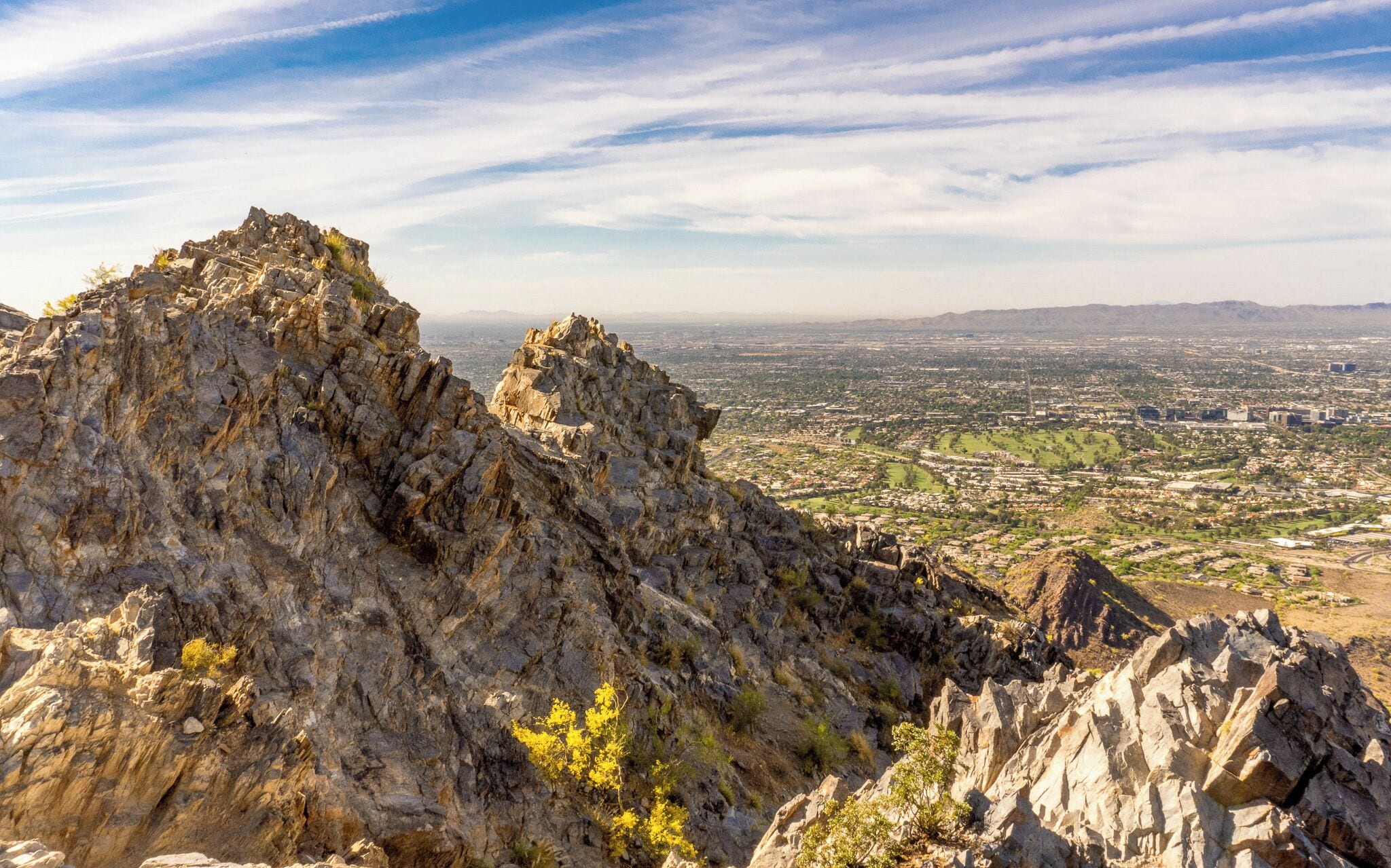 A rugged mountain landscape with rocky outcrops and a distant city view.