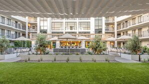 A multi-story hotel with outdoor seating, a central bar, and a covered patio area.