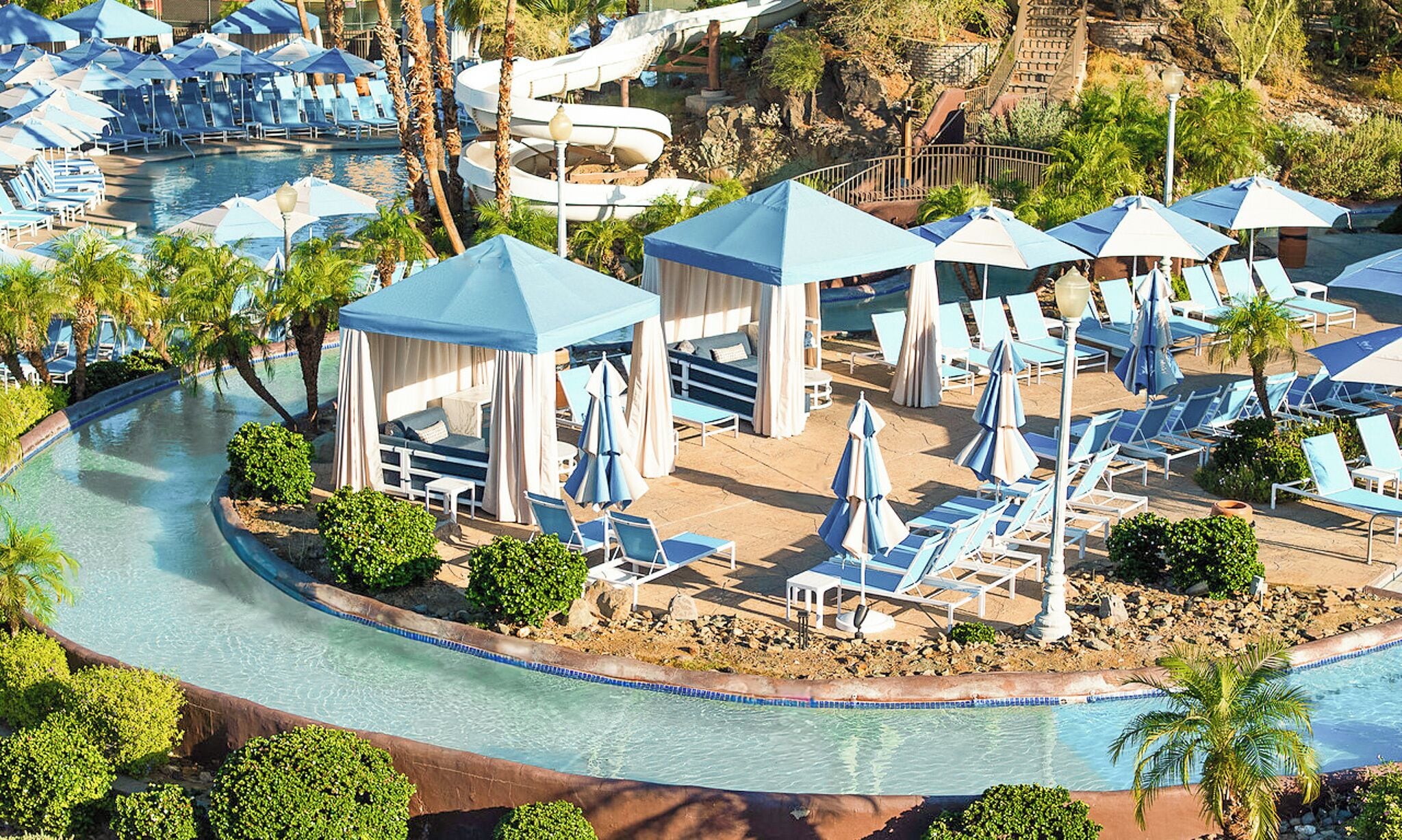 Un resort con piscina, sillas de descanso y cabañas.