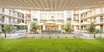 Pátio de hotel com área de estar ao ar livre, bar e piscina.