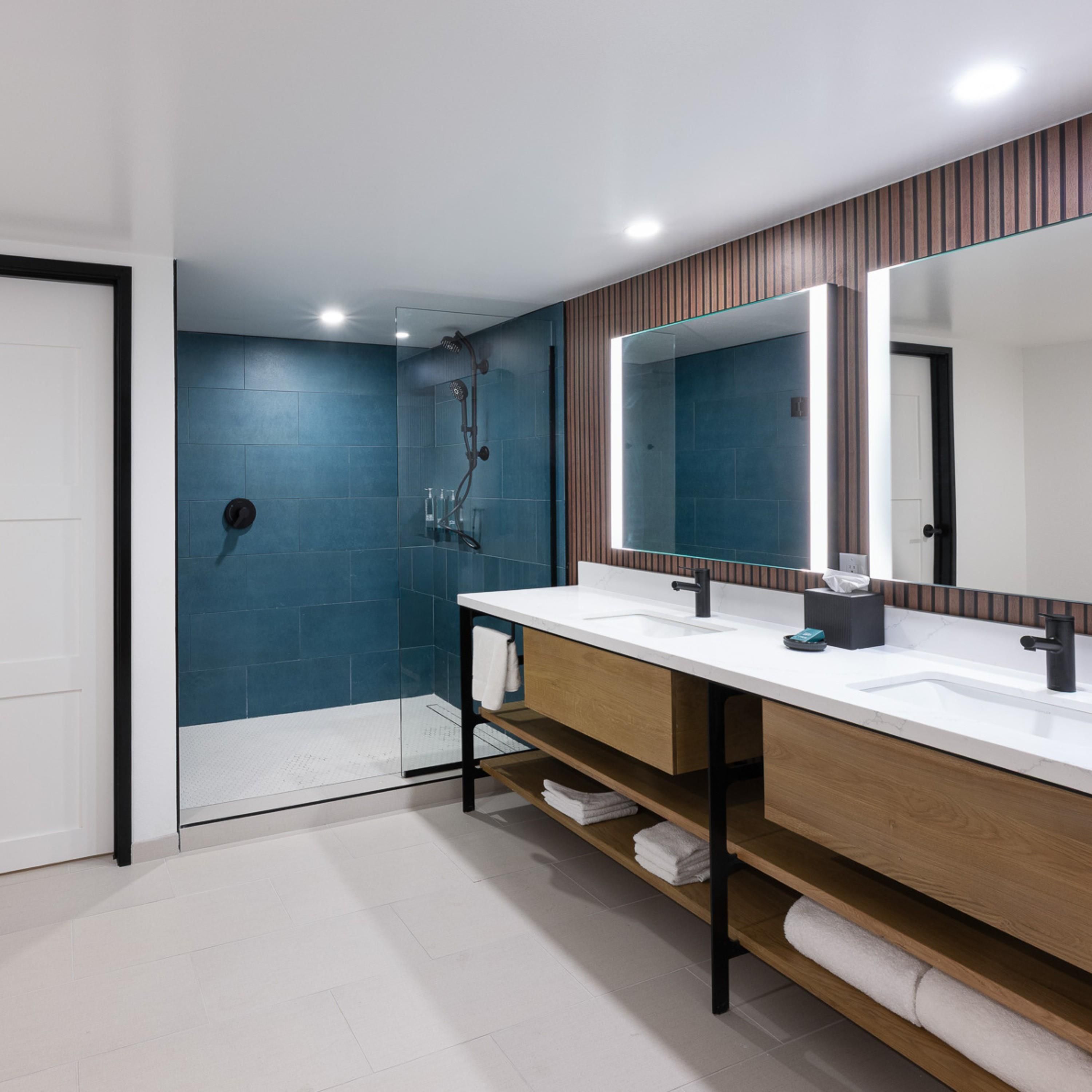A modern bathroom with a glass shower enclosure, two sinks, and a large mirror.