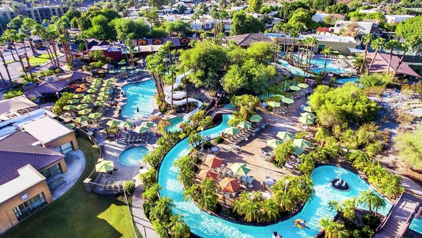 A resort with multiple swimming pools, palm trees, and lounge areas.