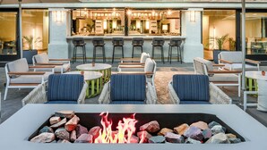 An outdoor seating area with a fire pit, bar, and lounge chairs.
