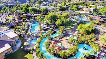 A resort with multiple swimming pools, palm trees, and lounge areas.