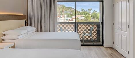 A hotel room with two beds, a balcony with a view, and a sliding door.
