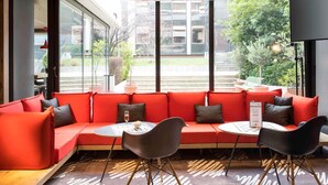 Um interior moderno com um sofá vermelho, cadeiras pretas e um tapete estampado.