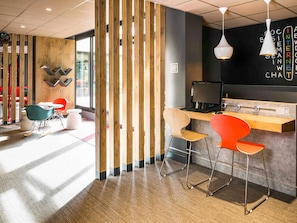A modern workspace with a wooden partition, a desk with a computer, and colorful chairs. - ibis Paris Pont De Suresnes (Suresnes)