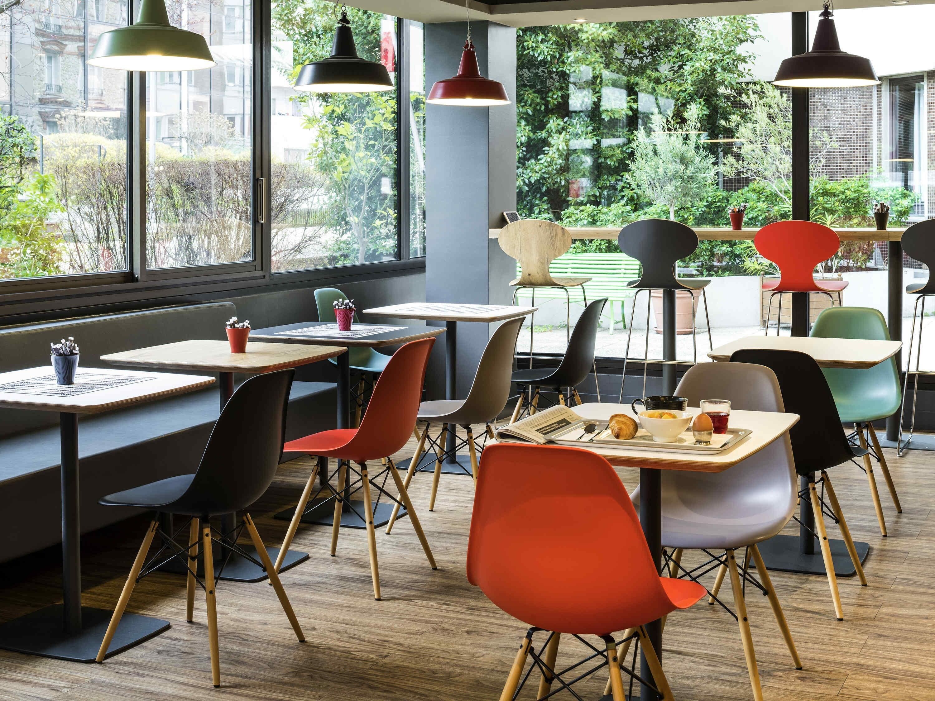 A modern cafe with tables, chairs, and hanging pendant lights.