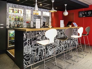A bar area with a black and white mural, a refrigerator with beverages, and modern bar stools. - ibis Paris Pont De Suresnes (Suresnes)