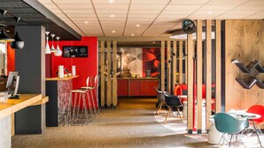 A modern interior with a reception desk, bar area, and seating. - ibis Paris Pont De Suresnes (Suresnes)