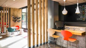 Um espaço de trabalho moderno com divisória de madeira, uma mesa com computador e cadeiras coloridas.