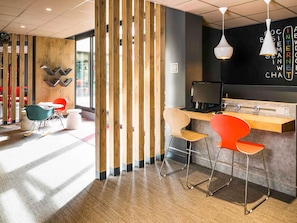 Un interior moderno con un separador de madera, una recepción y una zona de estar con sillas.
