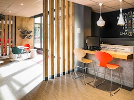Un interior moderno con un separador de madera, una recepción y una zona de estar con sillas.