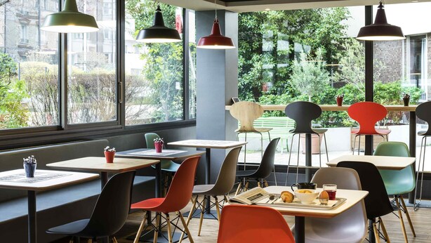 Um café moderno com mesas, cadeiras e luminárias pendentes.