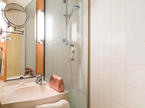 Un baño con lavamanos, espejo y ducha.