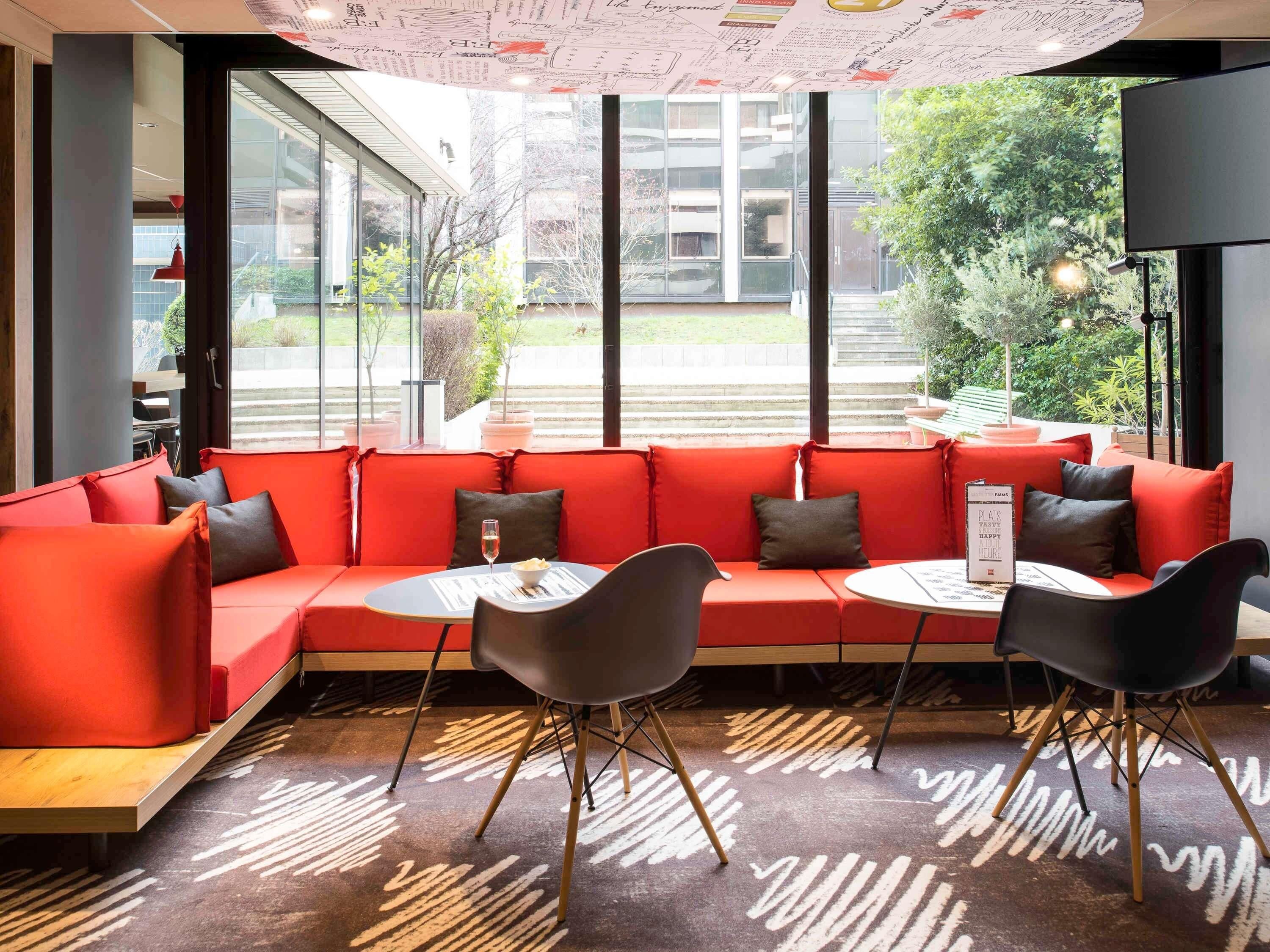 A modern interior with a red sofa, black chairs, and a patterned carpet.