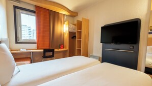 A hotel room with two beds, a desk, a chair, a TV, and a wardrobe. - ibis Paris Pont De Suresnes (Suresnes)